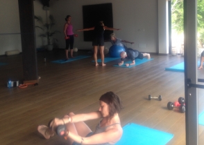 A studio class on mats, one person doing sit-ups in the foreground.