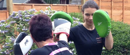 Gemma holding boxing pads for a client in a garden.