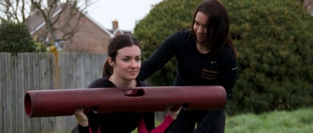 Gemma guiding a client holding a ViPR tube outdoors.